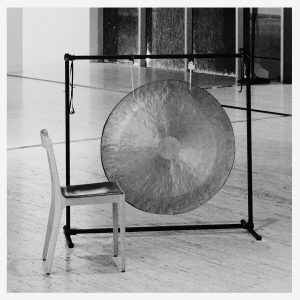 chair beside large hanging gong
